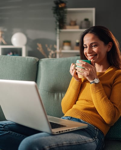 Resident relaxing on a sofa with a laptop in a cable- and high-speed-internet-ready Cleve Royale apartment