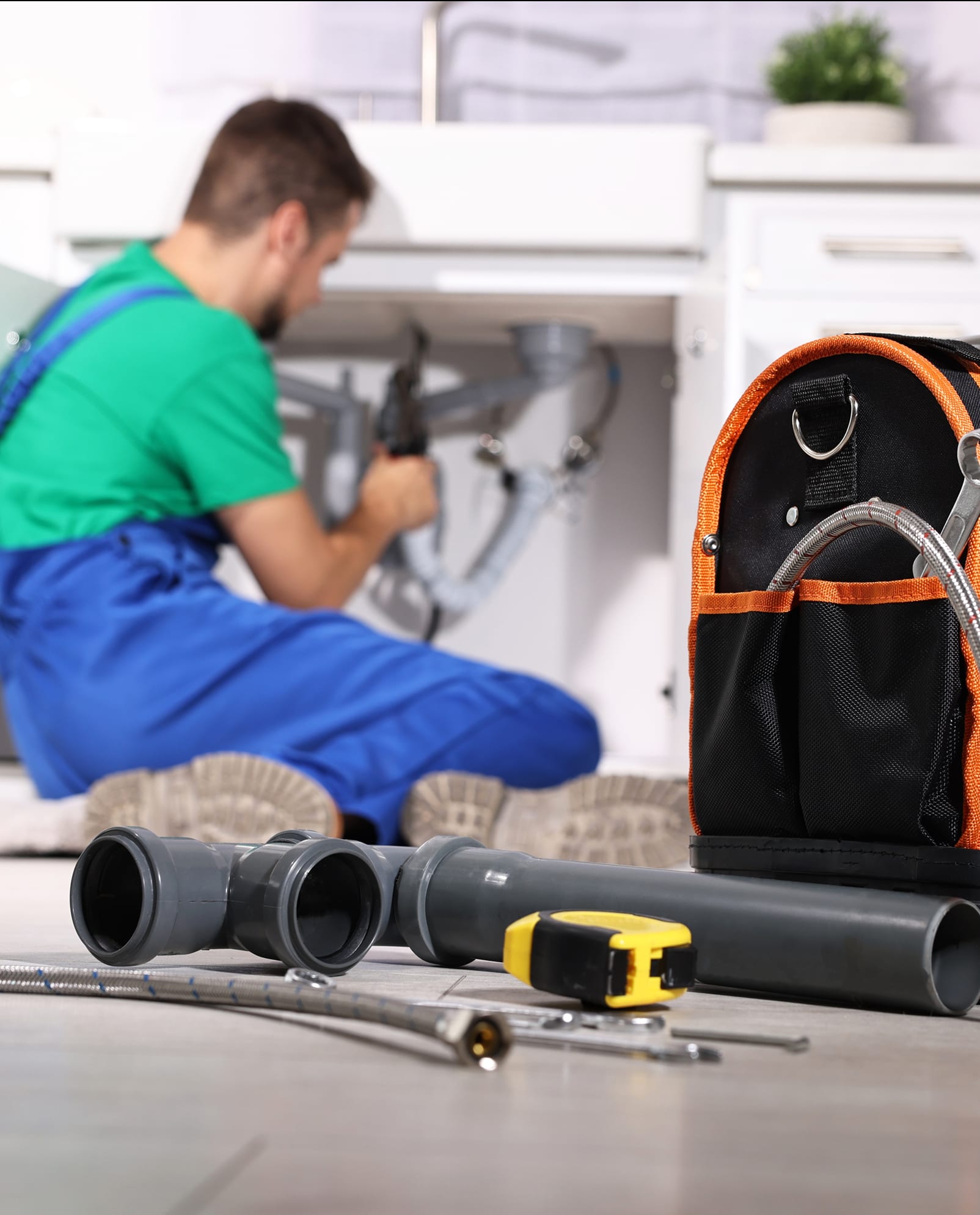 On-site maintenance technician repairing plumbing under a kitchen sink at Cleve Royale Apartments