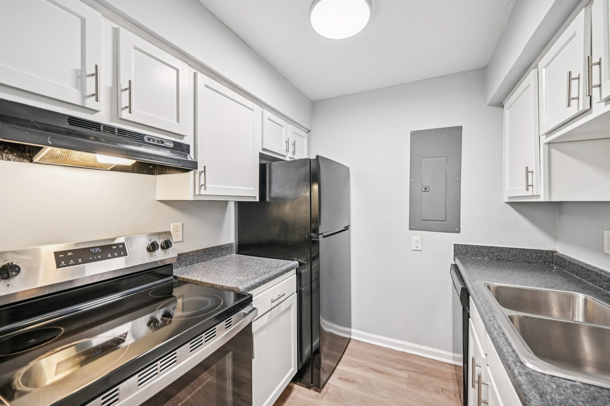 Renovated apartment kitchen with stainless steel range, refrigerator, and white cabinets at Cleve Royale Apartments