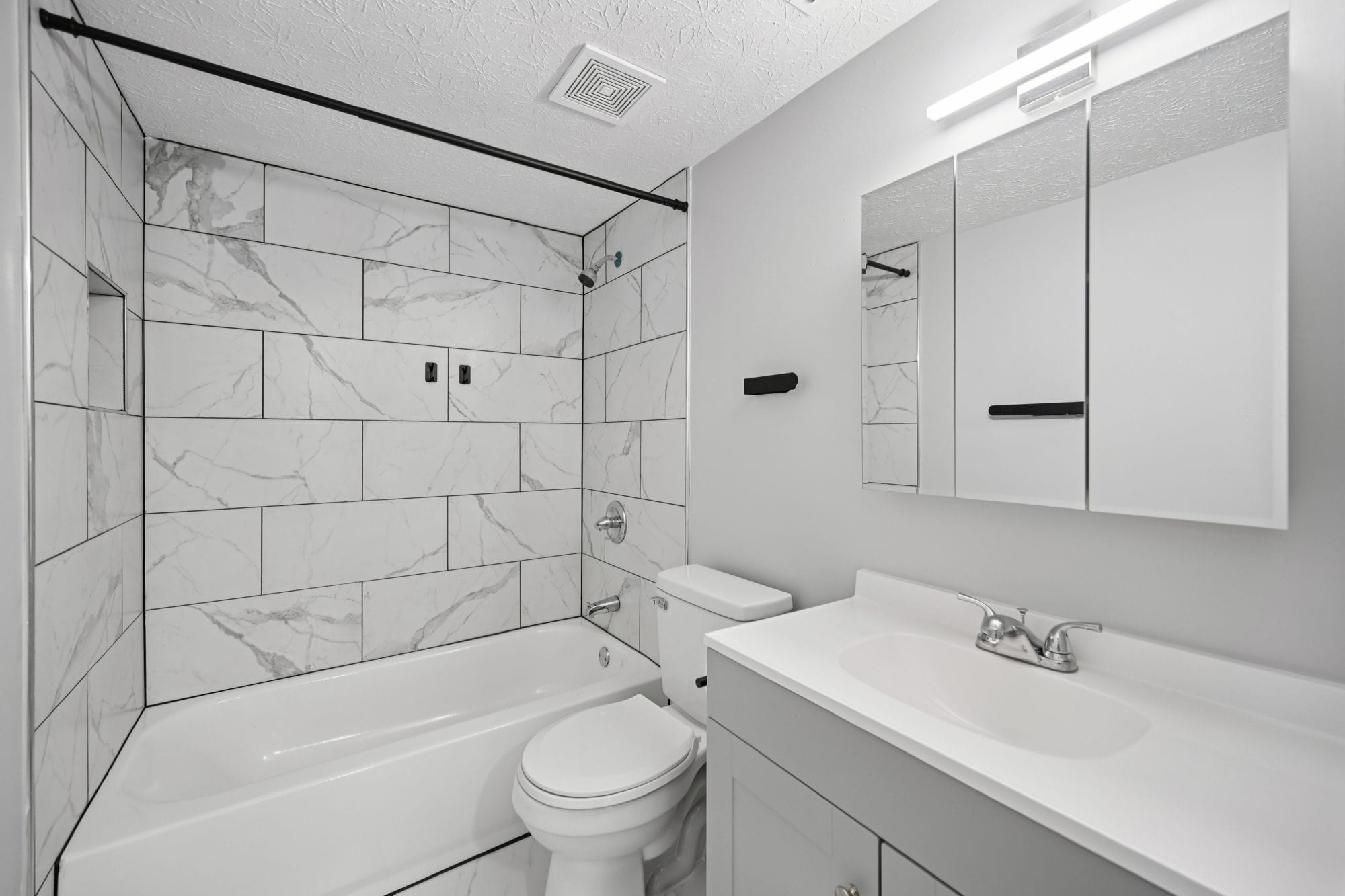 Newly renovated bathroom with marble-look tile, soaking tub, and modern vanity at Cleve Royale Apartments